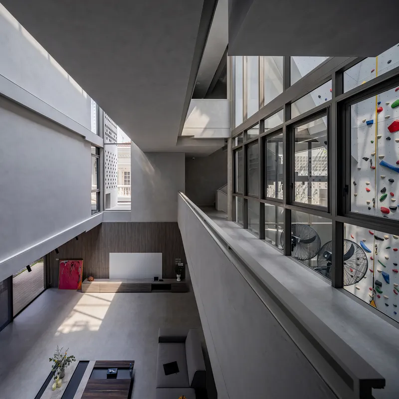 Double-height interior void with a steel-framed climbing wall visible through glazed partitions