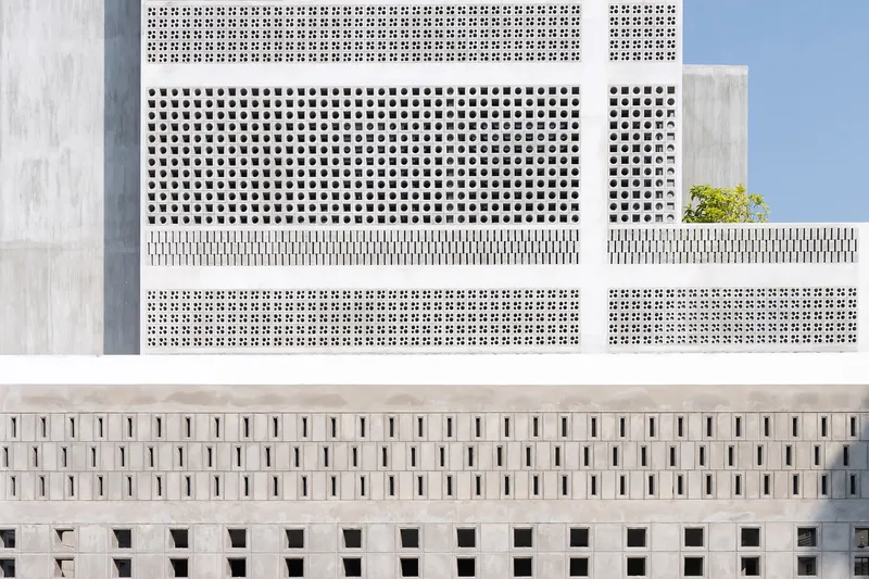Top-down view of patterned perforated concrete facades with varied opening sizes and small rooftop plantings