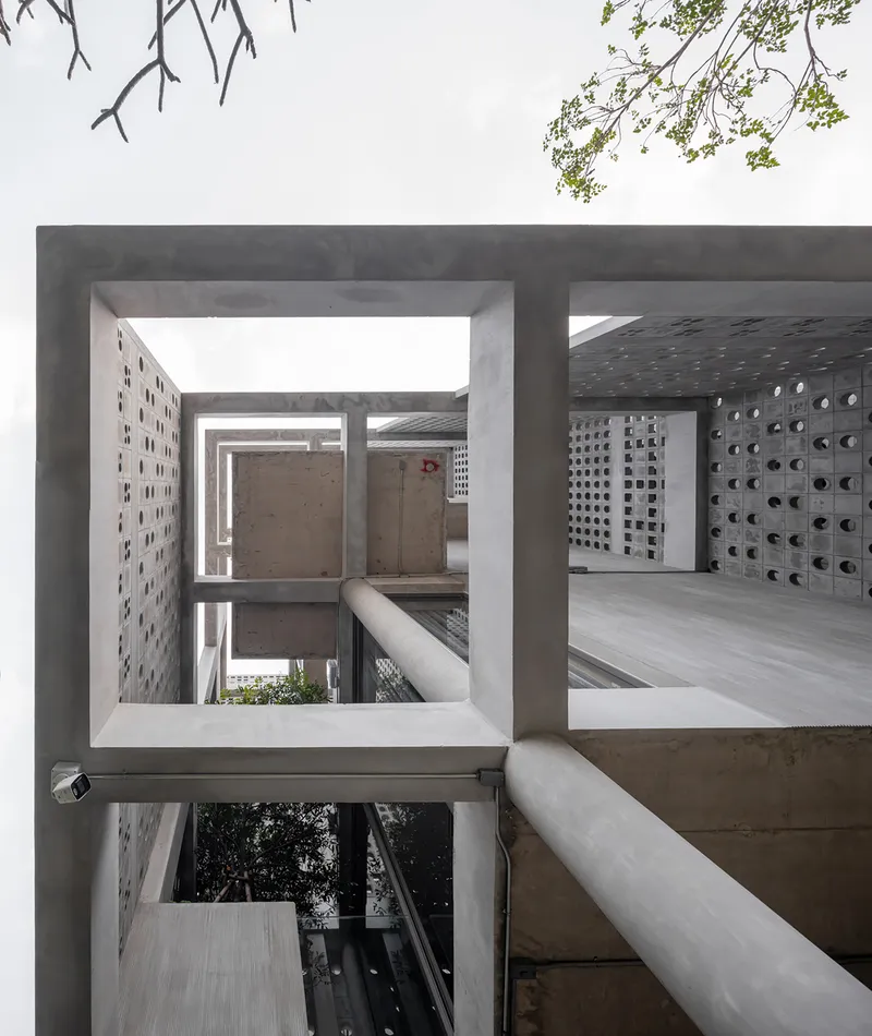 View through concrete framed openings showing perforated block walls and corridors with planted beds below