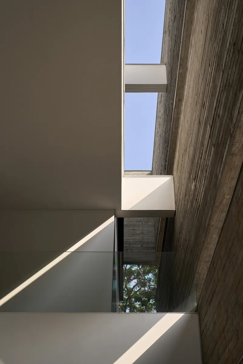 Interior stairwell skylight framed by board-formed concrete beams and white plaster walls
