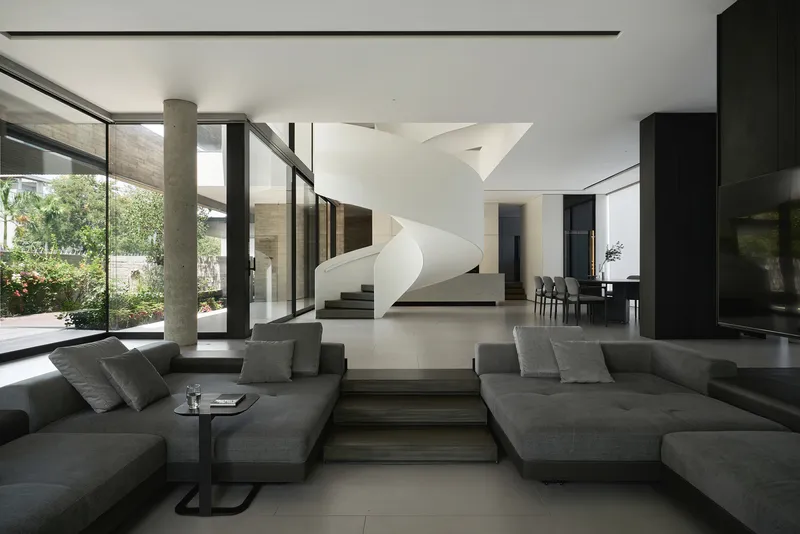 Double-height living room with a white helical staircase and floor-to-ceiling glass overlooking the garden