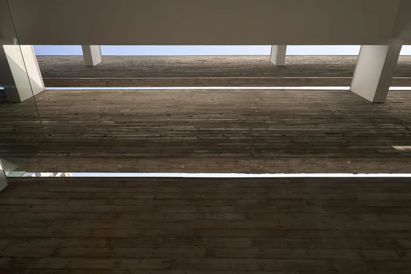 Upward view of timber bridge spanning between volumes under continuous skylight strips