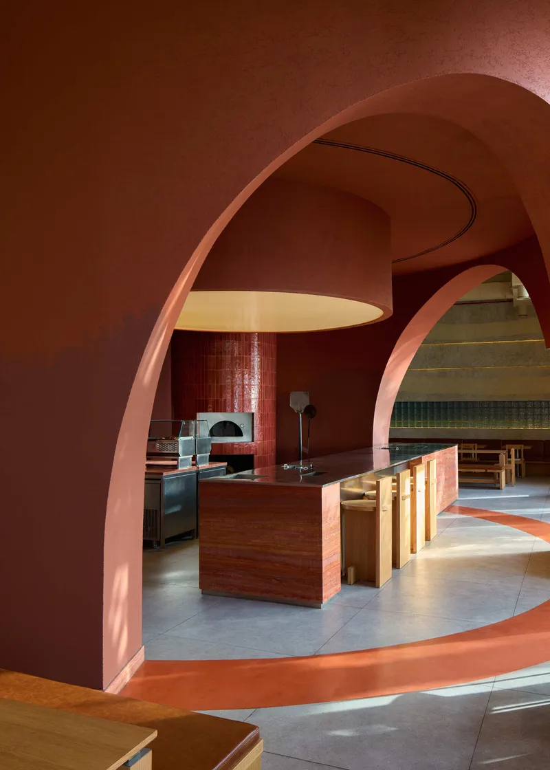 View through arched opening to dining area with timber furniture under a curved soffit and pendant light