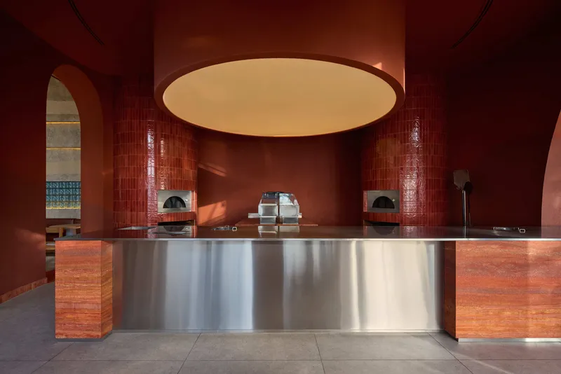 Long counter with brushed stainless steel front and timber ends under circular ceiling cutout with soft glow