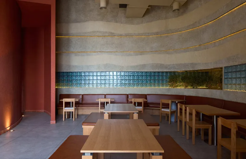 Dining area with timber tables and chairs along a curved wall with glass block ribbon window