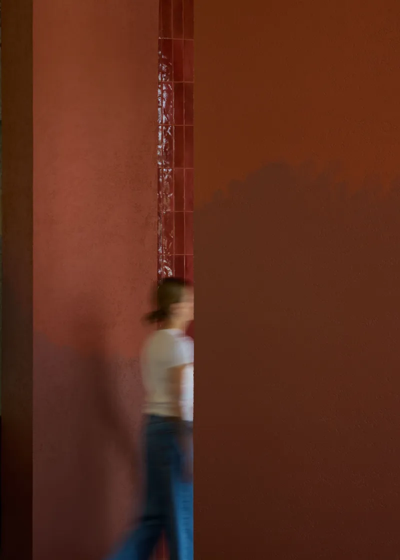 Narrow passageway with terracotta walls and a blurred figure in motion walking through