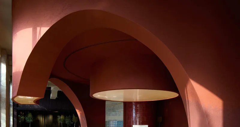 Rounded archway framing a pendant light in a terracotta interior with afternoon sunlight