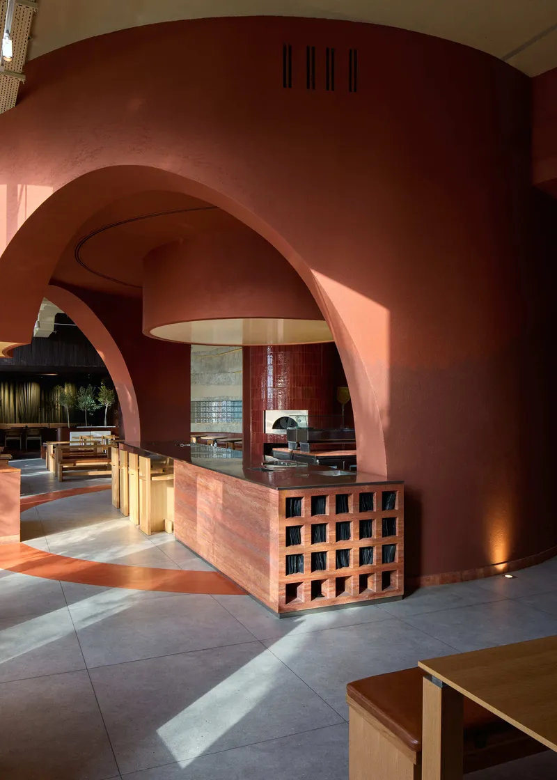 Reception counter with latticed base beneath layered terracotta arches and suspended pendant fixture