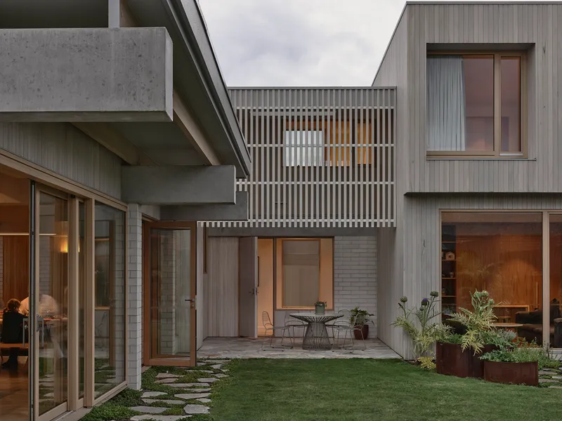 Central courtyard surrounded by vertical timber screens and concrete beams at dusk