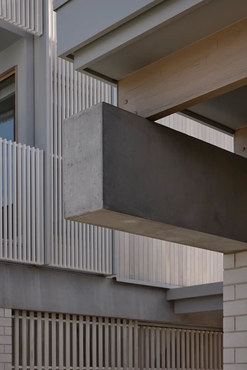 Close-up of cantilevered concrete balcony with timber soffit and vertical slatted screen above