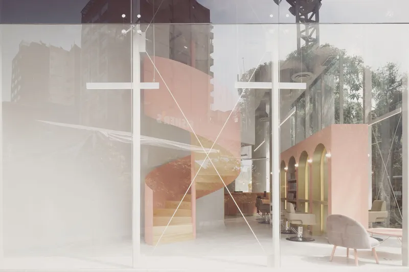 View through frosted glass panels showing the pink spiral stair and interior salon space beyond