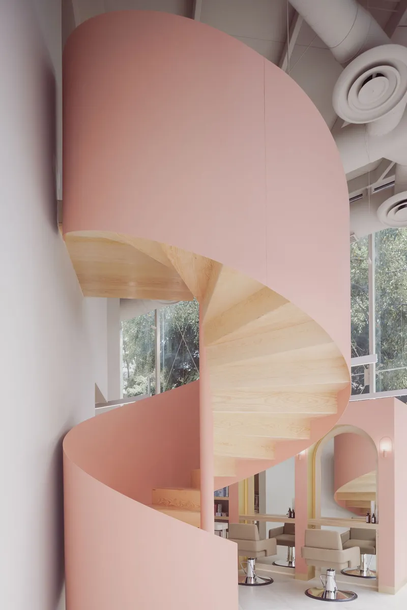 Helical timber stair wrapped by a pink curved soffit with views to the salon below