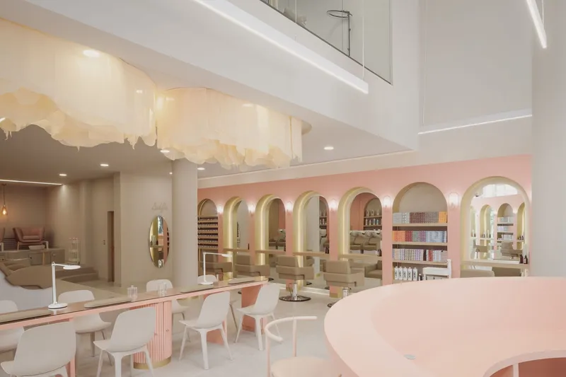Double-height interior with a pink arcaded wall, white seating area and mural on the ceiling