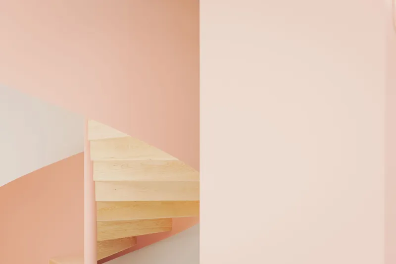 Detail of the light wood staircase treads framed by pink and white intersecting walls