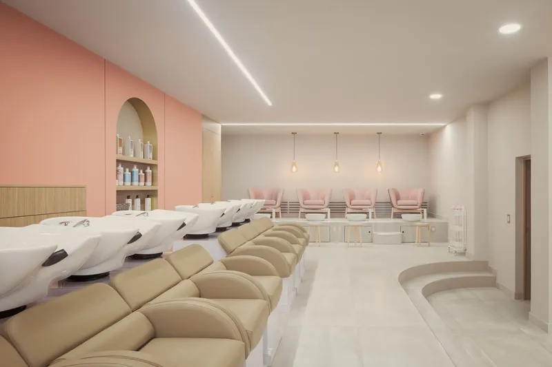 Salon interior with rows of hair-washing stations, pedicure chairs and pink millwork under linear lighting