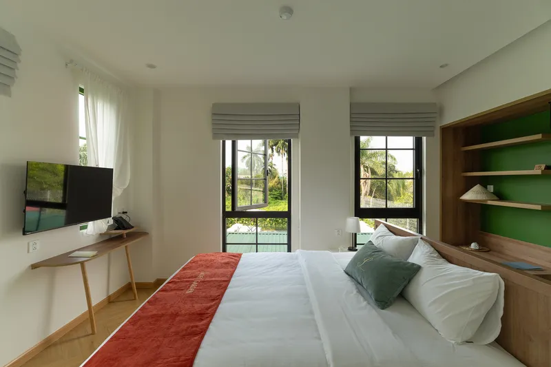 Bedroom interior with pale timber shelving, black-framed windows and views to palm trees outside
