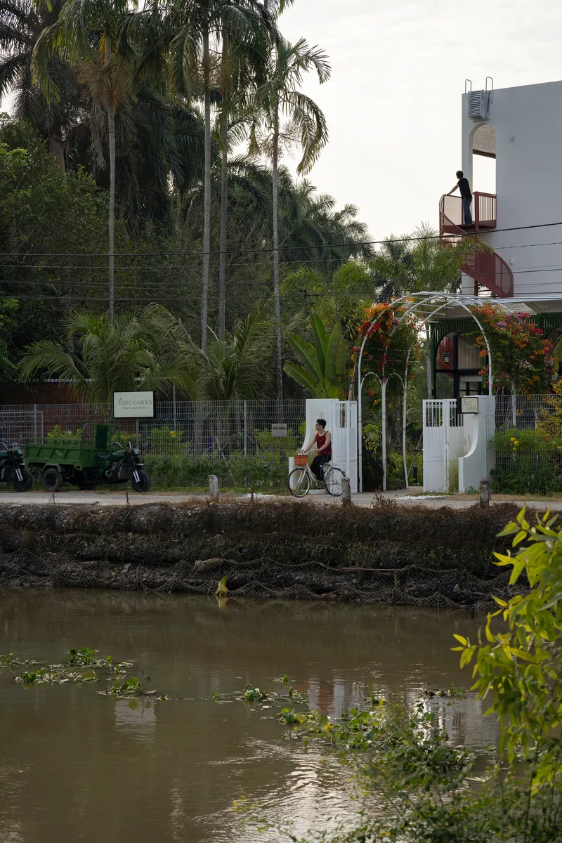 Street view across a canal showing the white arched entry gate with a cyclist passing by