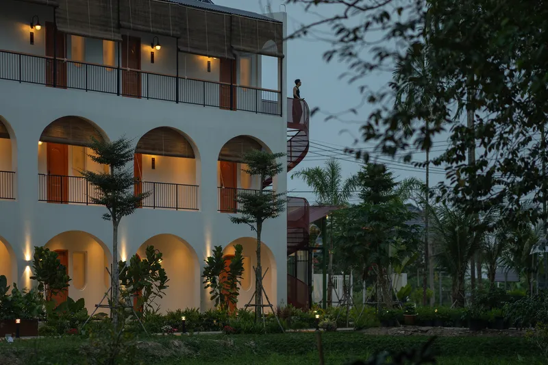 Courtyard elevation at dusk with arched openings, illuminated interiors and spiral stair tower