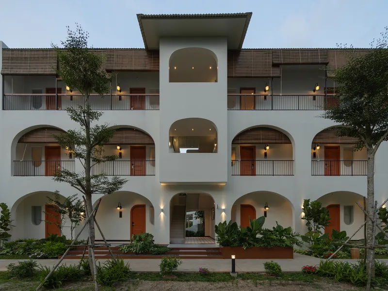 Symmetrical three-story facade with arched openings and central entrance pavilion at twilight
