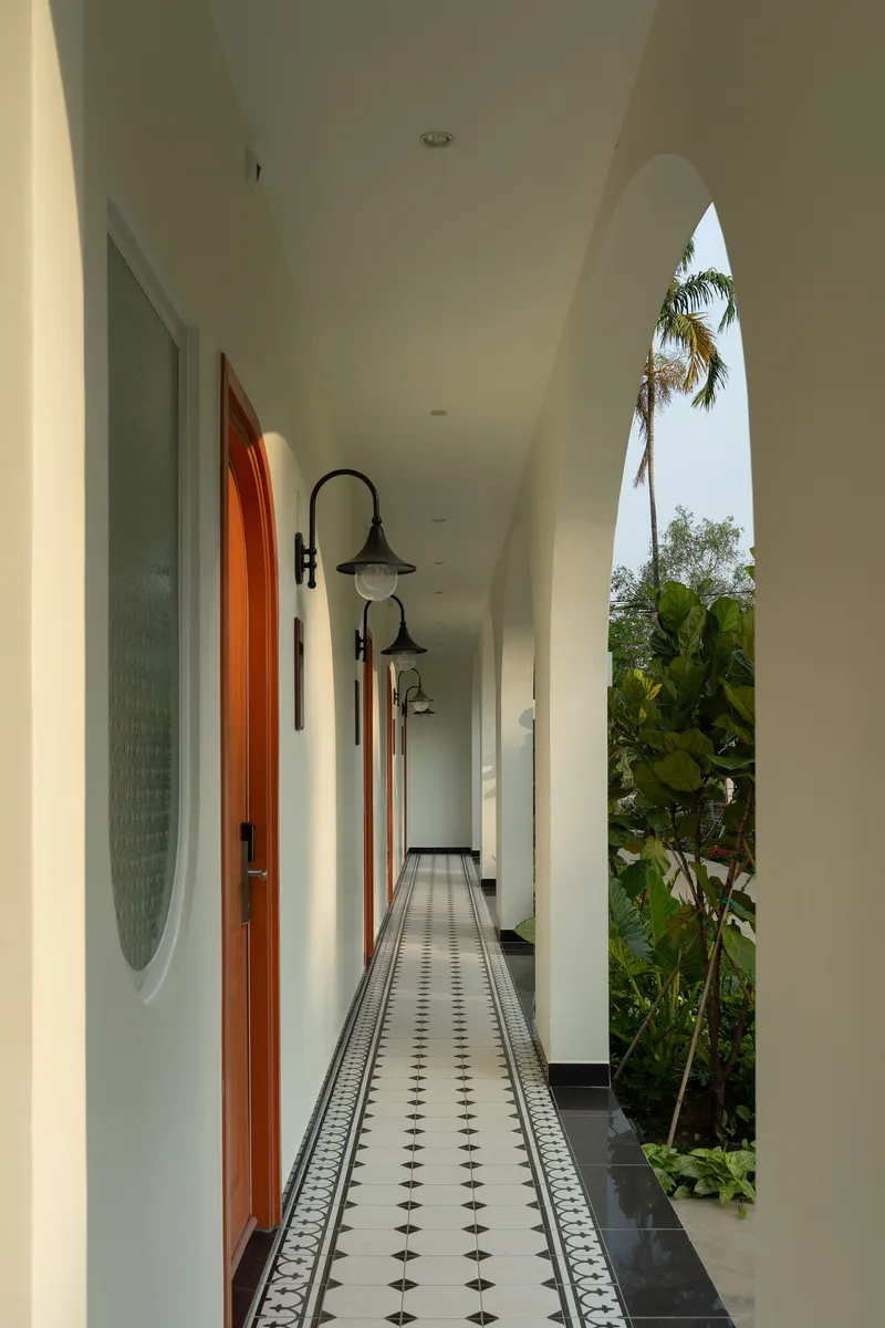 Covered corridor with patterned tile flooring and pointed arch opening revealing palm trees and banana plants