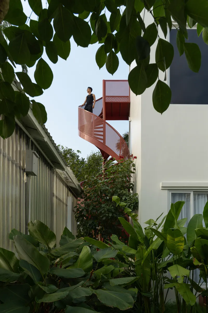 Upper landing of the spiral staircase framed by overhanging tree foliage and tropical plantings below