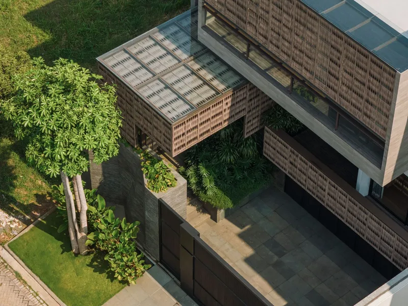 Aerial view of the brick-screened volumes framing a central courtyard with planted trees