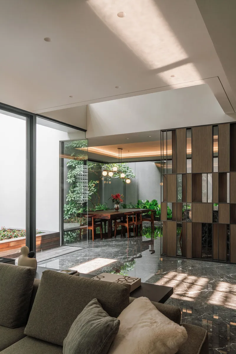Open-plan living space with timber screen divider and views to the planted courtyard beyond