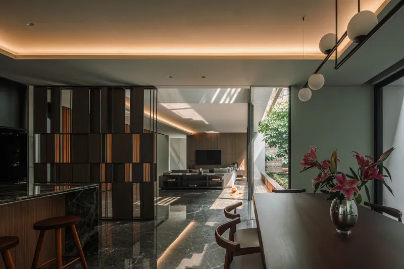 Dining area with timber and metal screen partition beneath a recessed ceiling cove with indirect lighting