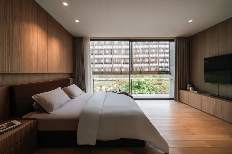 Bedroom with ribbed timber paneling and patterned screen window overlooking a garden