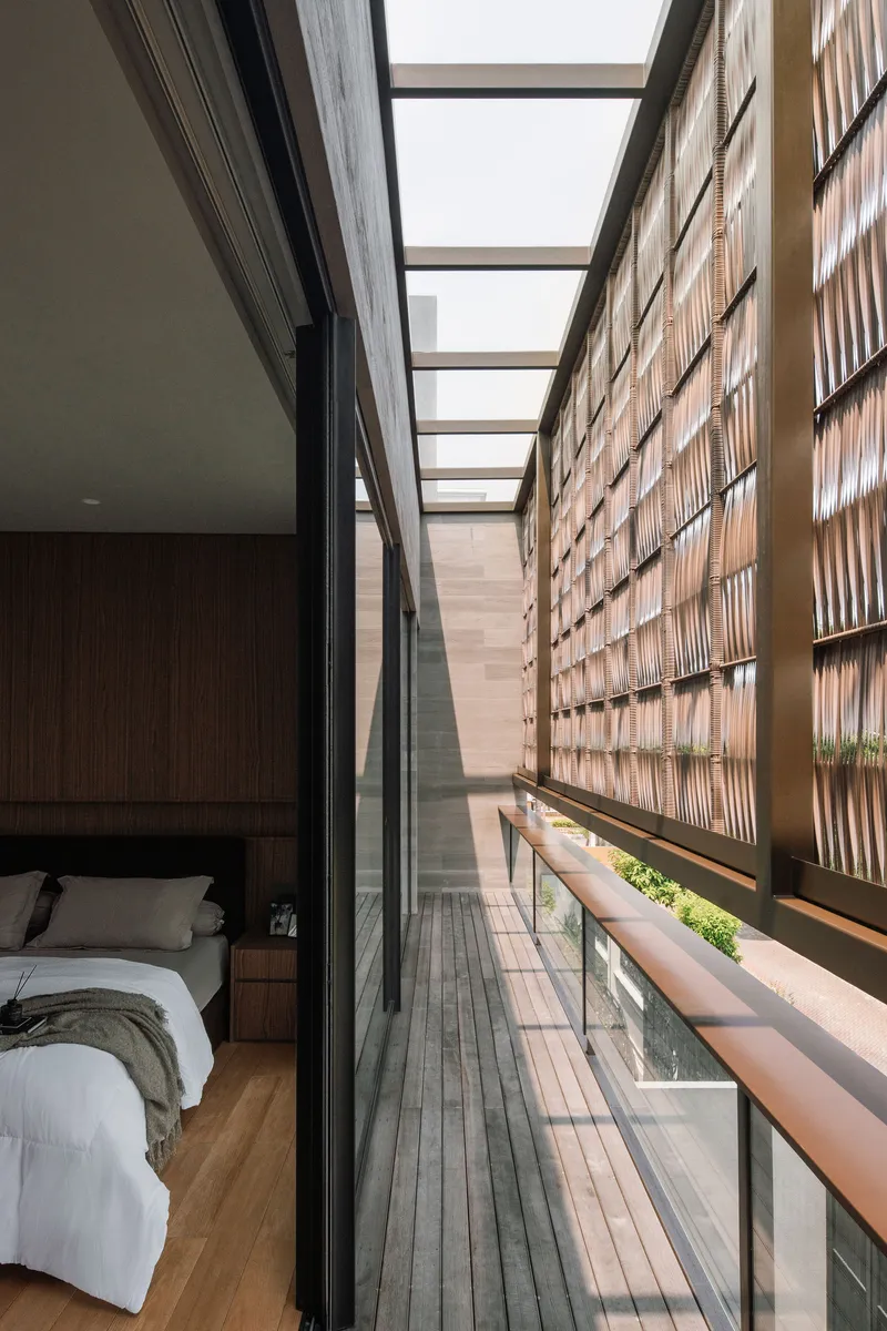 Narrow balcony with timber decking running alongside a bedroom and screened by a woven lattice wall
