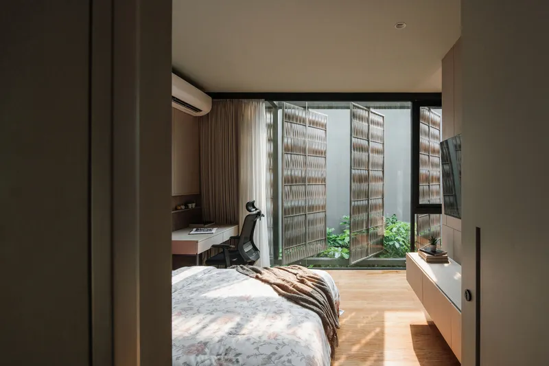 Bedroom view through open sliding doors to a courtyard with lattice screens and small planted garden