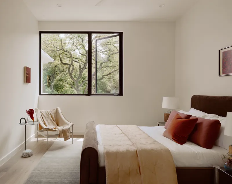 Bedroom with corner window framing a view of oak tree branches