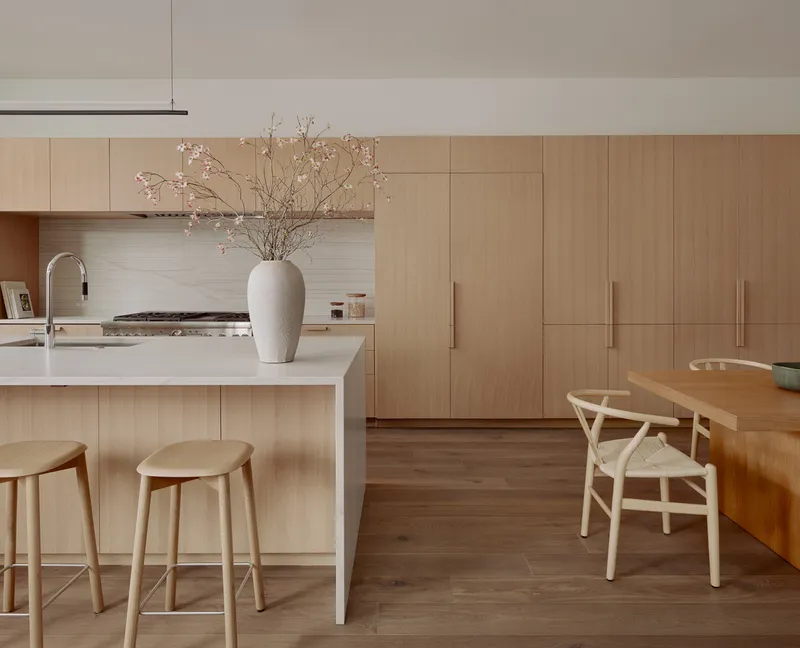Kitchen island with pale wood cabinetry and a vase of cherry blossoms