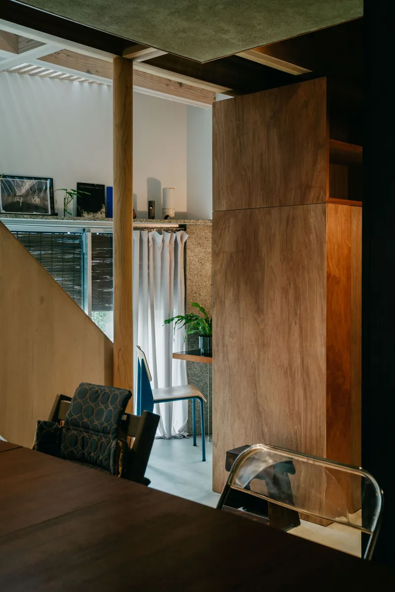 Split-level interior with walnut millwork and exposed timber columns framing curtained openings