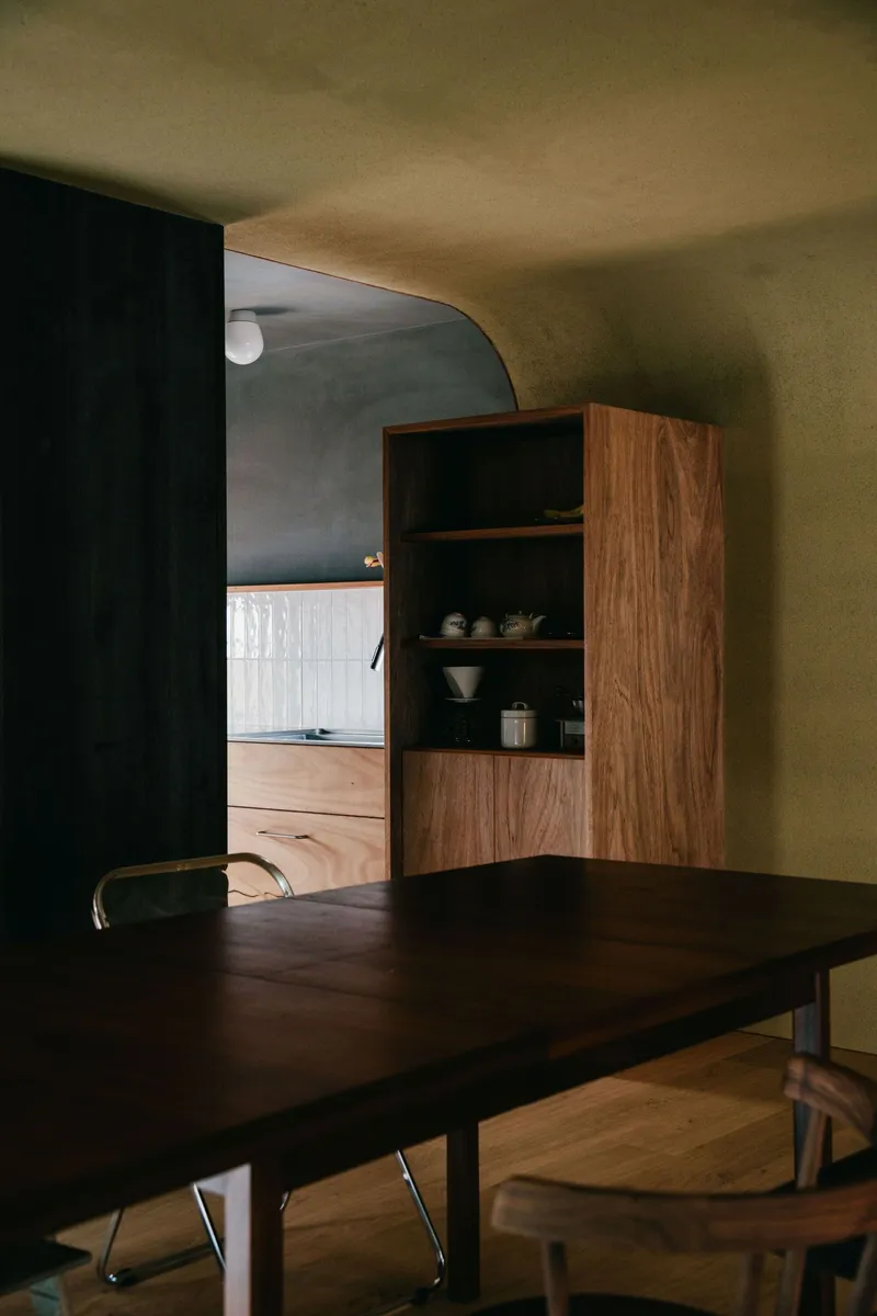 Walnut dining table and built-in shelving with arched doorway opening to adjacent room