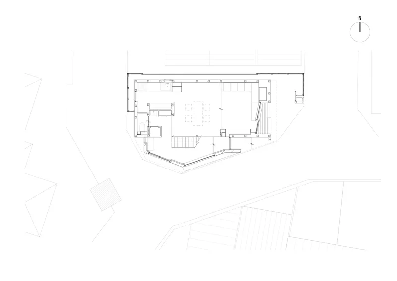 Floor plan drawing showing an angled rectangular volume with central staircase and surrounding site context