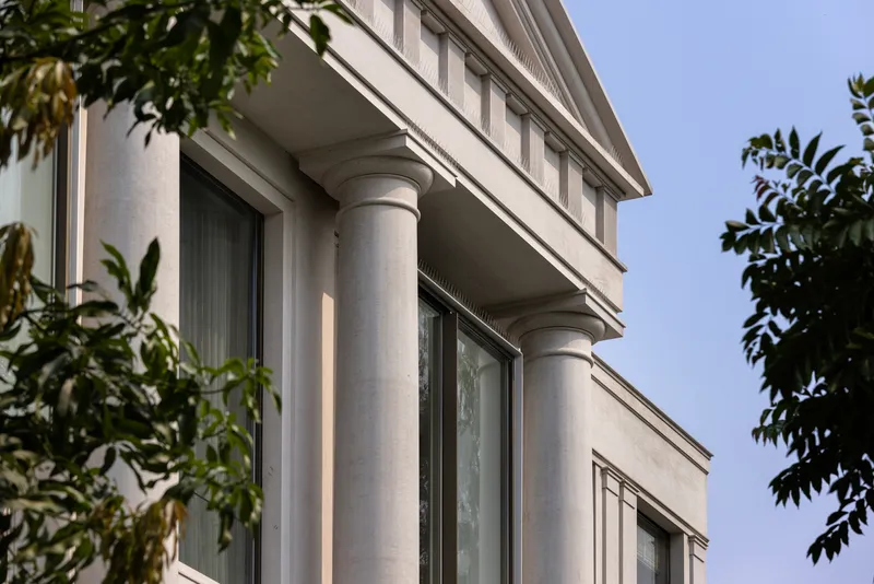 Detail of stacked terraces with stone columns supporting continuous balconies beneath overcast sky