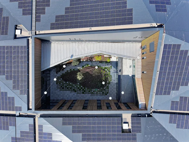 Aerial view of internal courtyard with plantings and pavers surrounded by solar panel roof surface