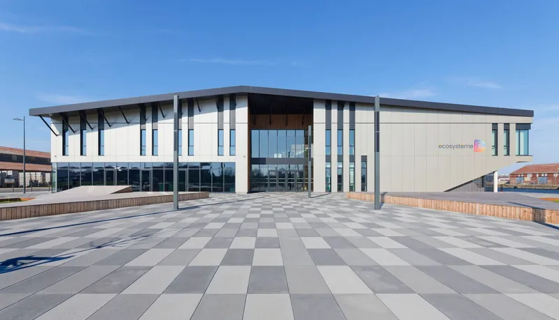 Main entrance plaza with chequered paving and cantilevered canopy on a clear day