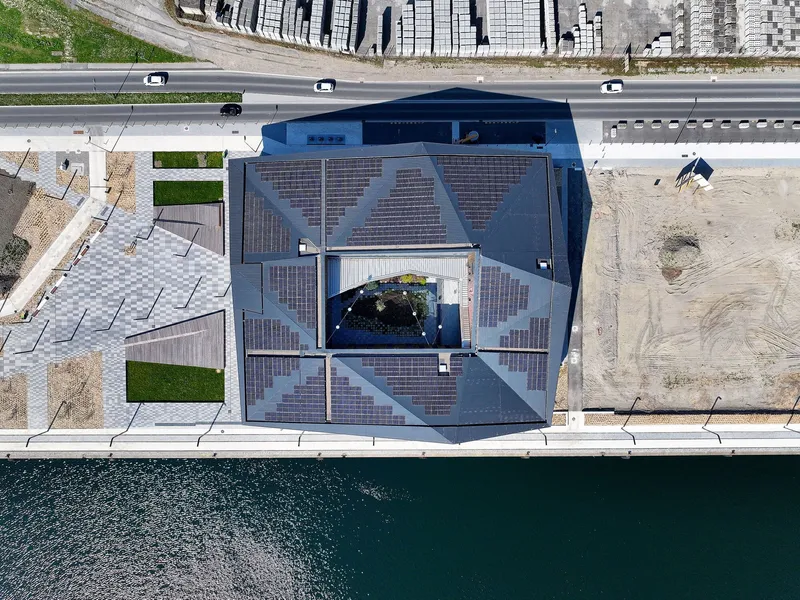 Aerial view of the faceted solar panel roof between waterfront quay and roadway with traffic