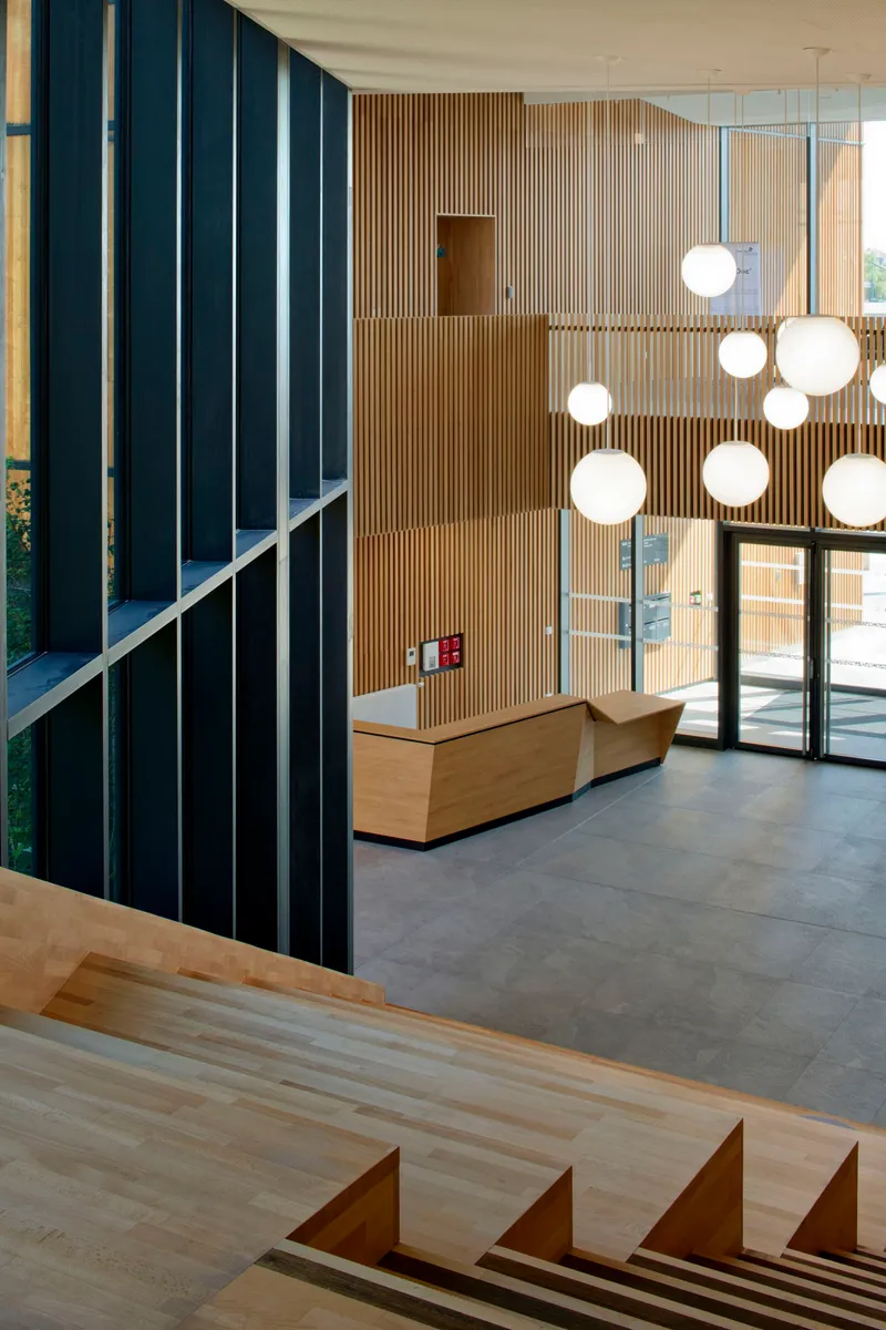 Double-height lobby with sphere pendant lights and timber staircase visible in foreground