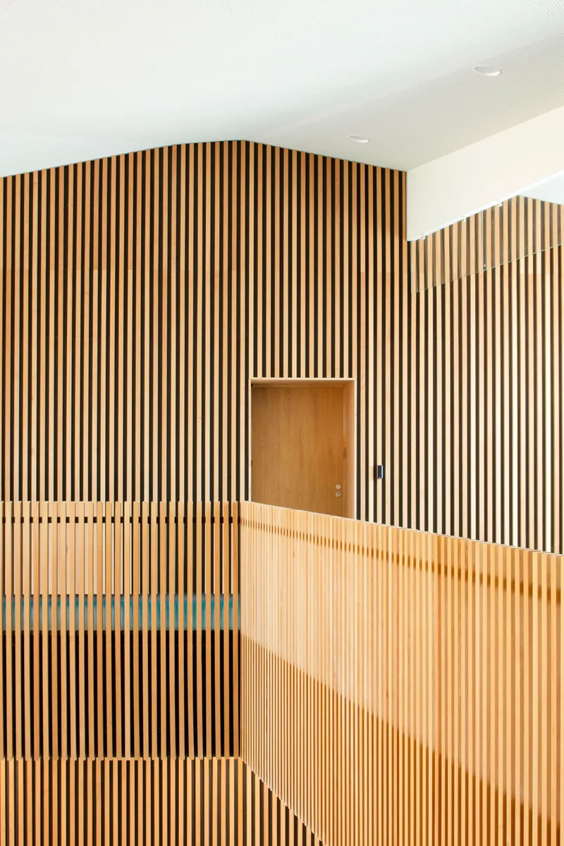 Vertical timber slatted wall with recessed door opening and glazed balustrade below