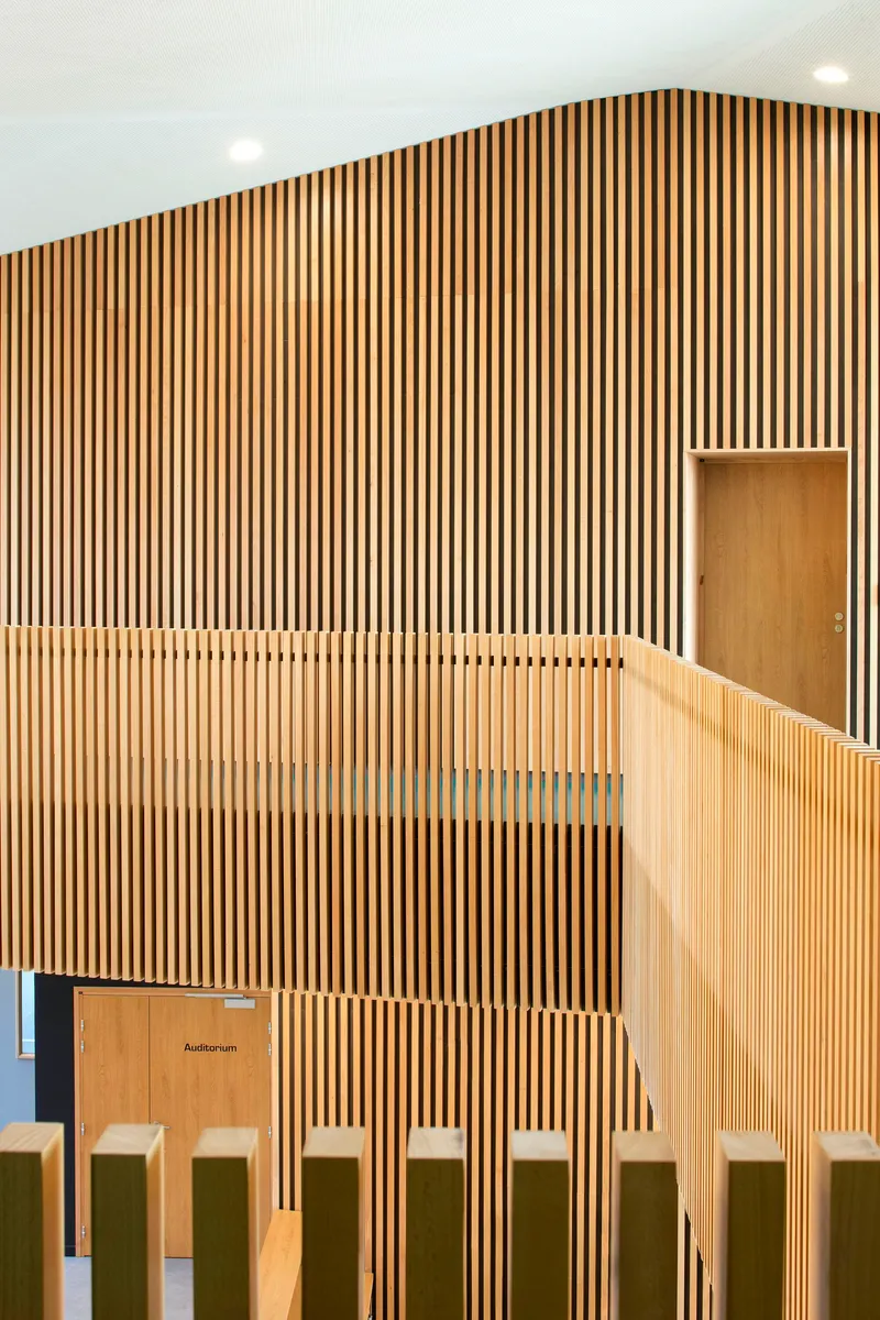 Angled view of timber slat wall showing recessed door and balustrade top rail