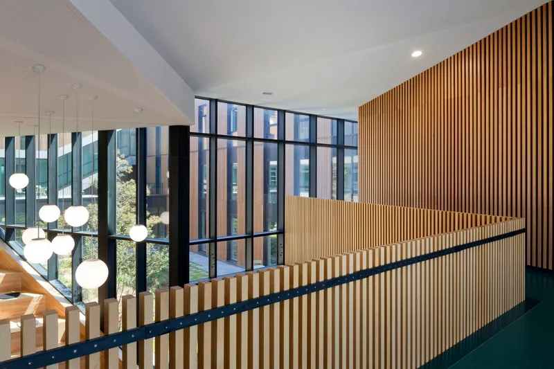 Upper level landing with timber slat wall and black steel handrail overlooking courtyard