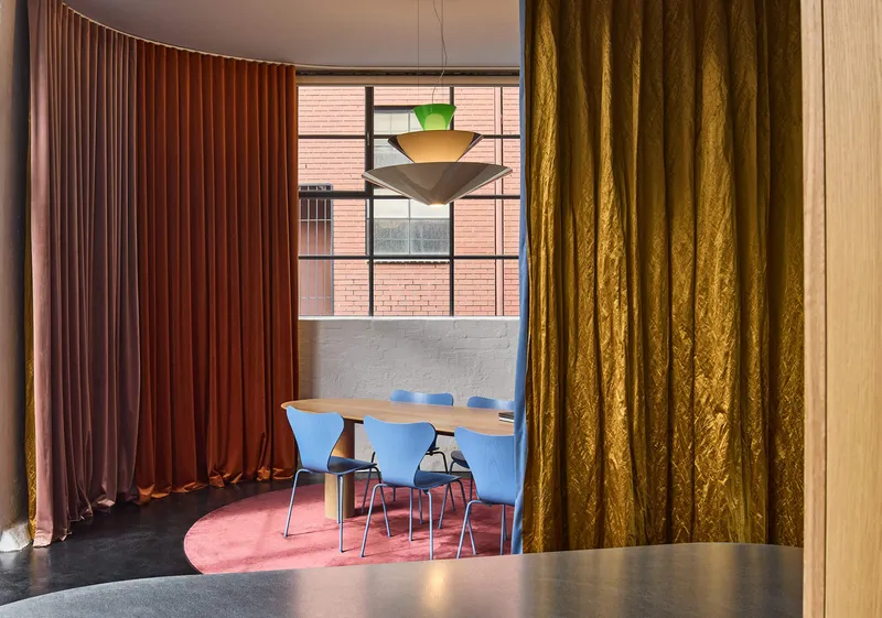 View through golden curtain towards seating area with layered textile partitions in varied hues