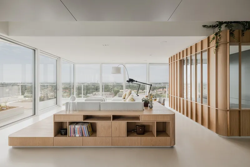 Elevated timber platform with integrated seating and storage facing floor-to-ceiling windows overlooking distant greenery