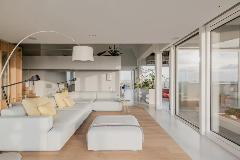 Seating area opening onto a terrace through sliding glass doors under soft daylight