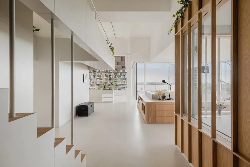 Open interior with timber and glass partition wall alongside a floating white staircase