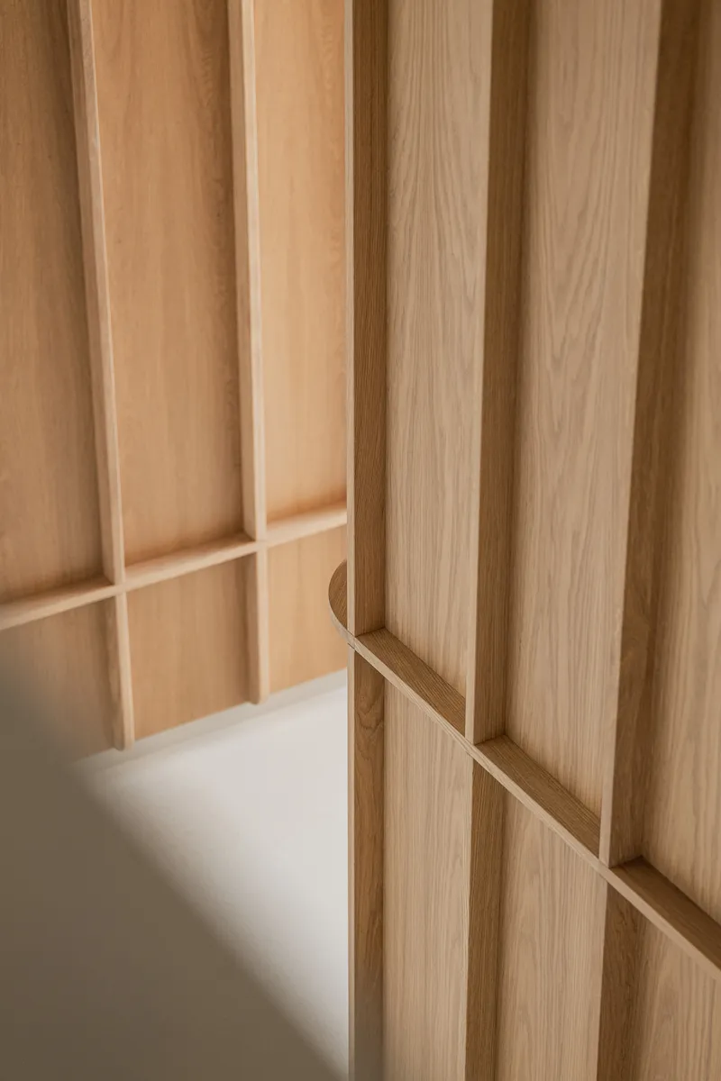 Close-up of recessed timber handle integrated into the vertical wood panel joinery