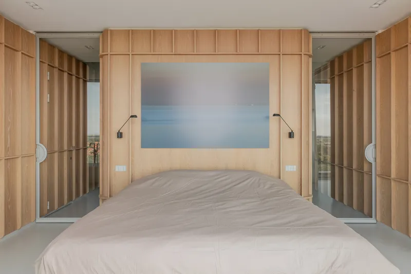 Bedroom with vertical timber paneling flanking the bed and mirrored sliding doors on each side